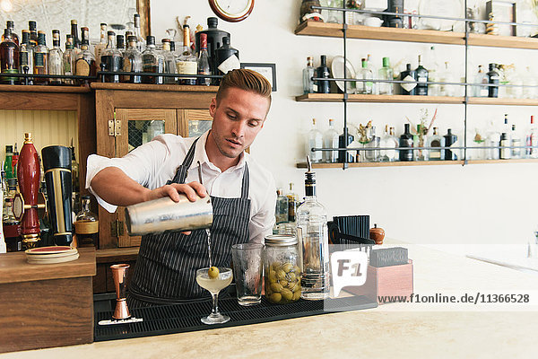 Männlicher Barkeeper beim Einschenken von Cocktails an der Cocktailbar