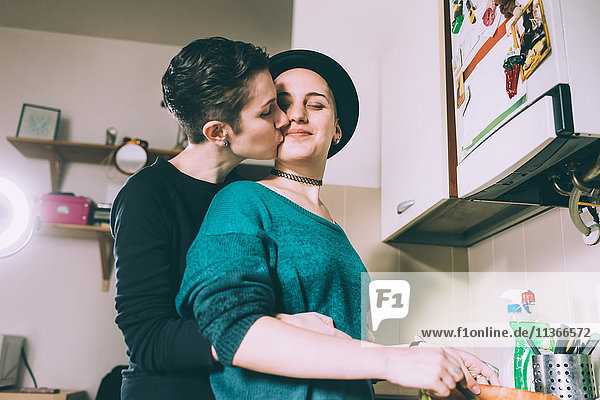 Junge Frau küsst Freundin in Küche