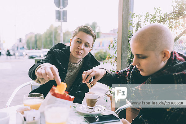 Zwei Freundinnen essen einen Snack im Straßencafé.