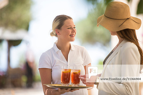 Boutique hotel waitress welcoming young woman with drinks  Majorca  Spain