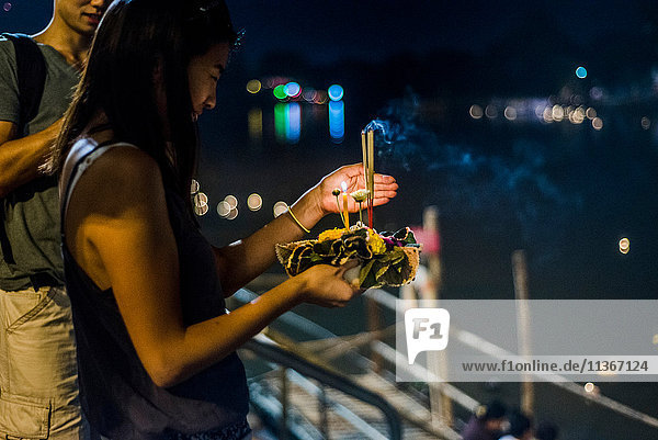 Junge Frau am Ping-Fluss in Chiang Mai während des Loy Krathong Laternenfestivals  bei dem eine schwimmende Laterne den Ping-Fluss hinuntergelassen wird  Chiang Mai  Thailand