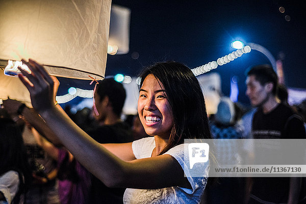 Junge Frau hält brennende Papierlaterne in der Hand und wartet auf ihre Freilassung beim Loy Krathong Paper Latern Festival in Chiang Mai  Thailand