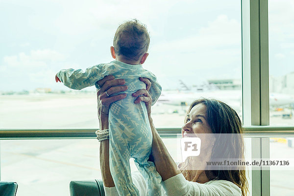 Großmutter hebt Baby in der Luft am Flughafen