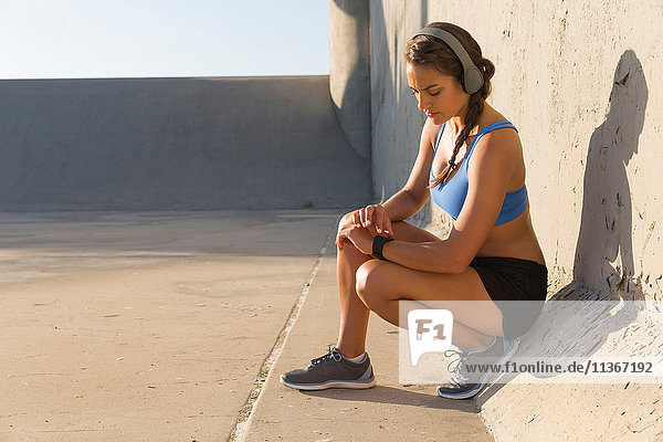 Sportlerin mit Kopfhörern bei der Kontrolle der Smartwatch
