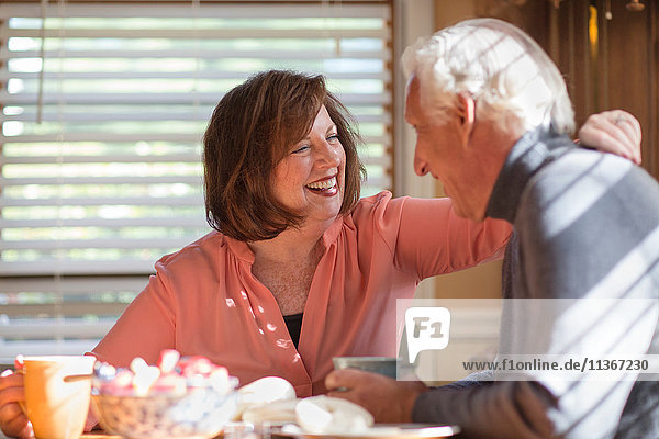 Senior couple laughing together at kitchen table