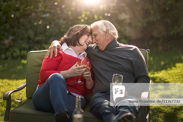 Romantisches Seniorenpaar sitzt von Angesicht zu Angesicht auf dem Sofa im Garten