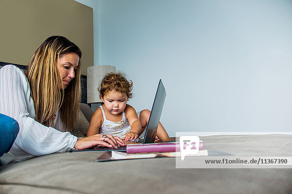 Mutter benutzt Laptop im Bett mit Tochter
