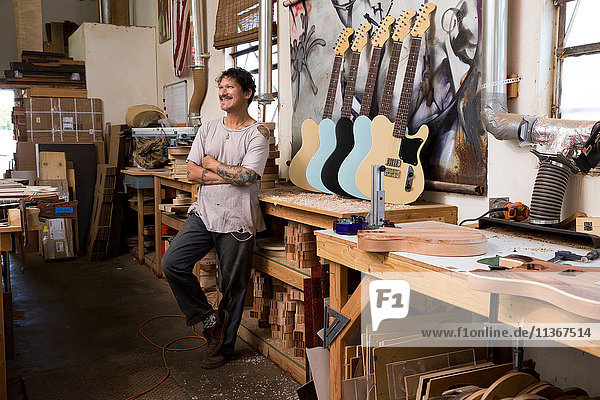 Gitarrenbauer in der Werkstatt schaut lächelnd weg