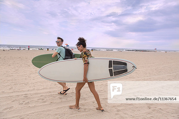 Junges Paar mit Surfbrettern am Rockaway Beach  New York State  USA