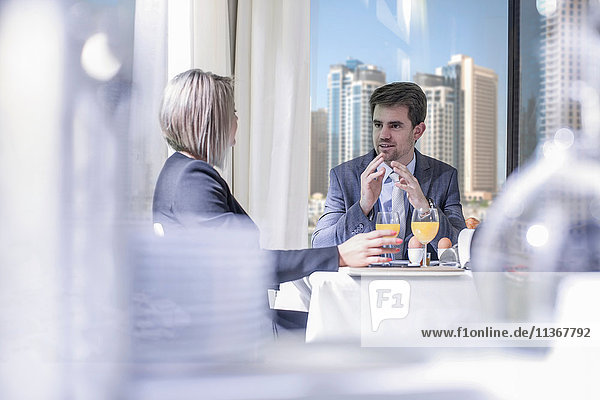 Businessman and woman having breakfast meeting in hotel restaurant