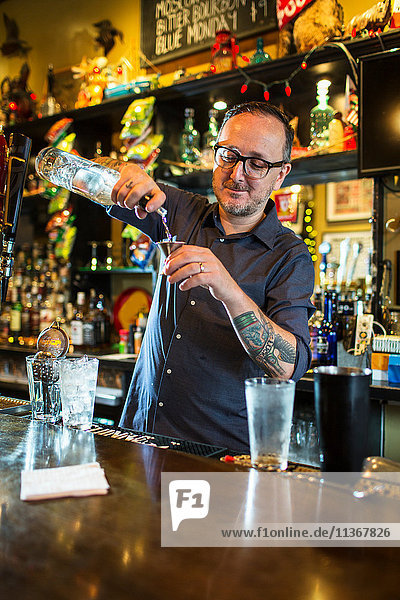 Barkeeper bereitet Cocktail am Tresen einer Gaststätte zu
