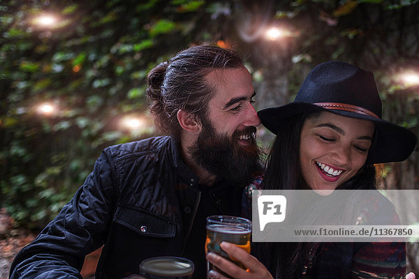 Young couple laughing in beer garden in evening  Brooklyn  New York  USA
