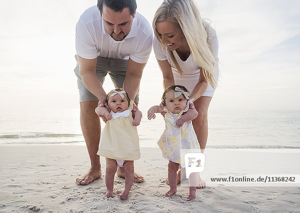 Happy family with two baby girls (2-5 months) at beach