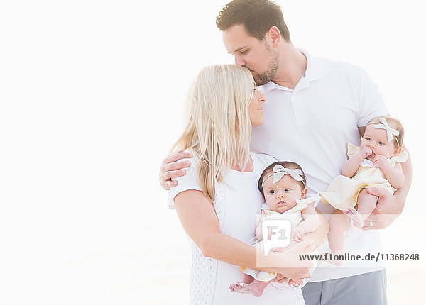 Studioaufnahme einer glücklichen Familie mit zwei kleinen Mädchen (2-5 Monate) auf weißem Hintergrund