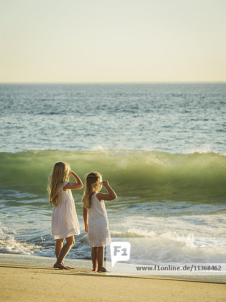 Mädchen (4-5  6-7) stehen am Strand und schauen aufs Meer