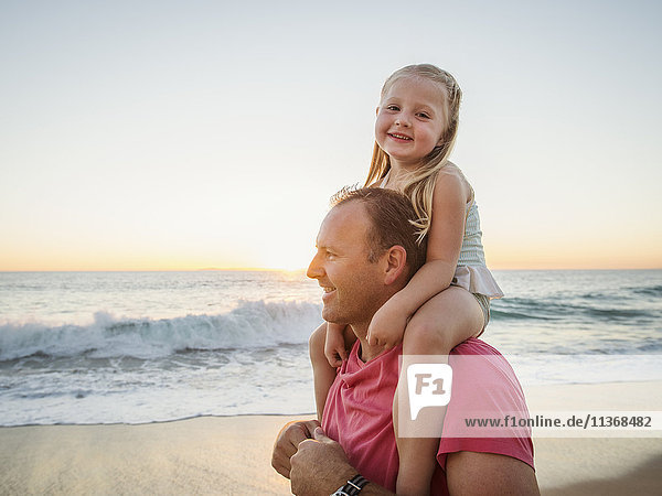 Vater trägt Tochter (4-5) am Strand