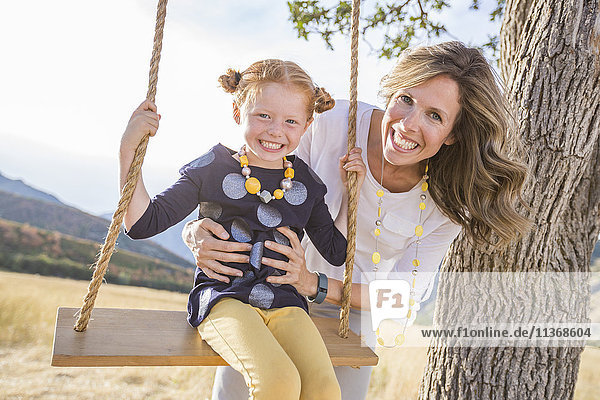 Mother with girl (4-5) sitting on swing