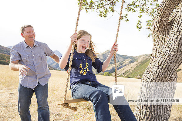 Father with daughter (8-9) sitting on swing
