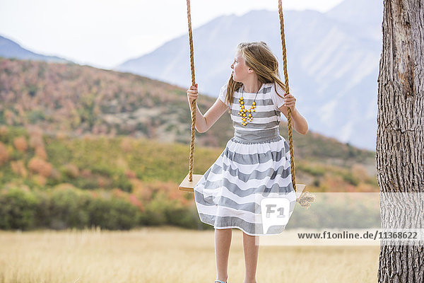 Girl (8-9) sitting on swing