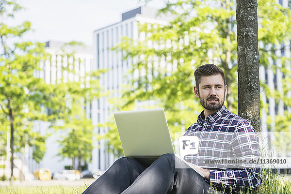 Young man working on laptop and sitting in park