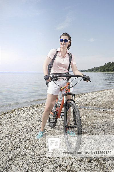 Ältere Frau mit Fahrrad am Seeufer