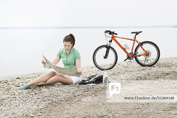 Mature woman with electric bike by lake looking at road map