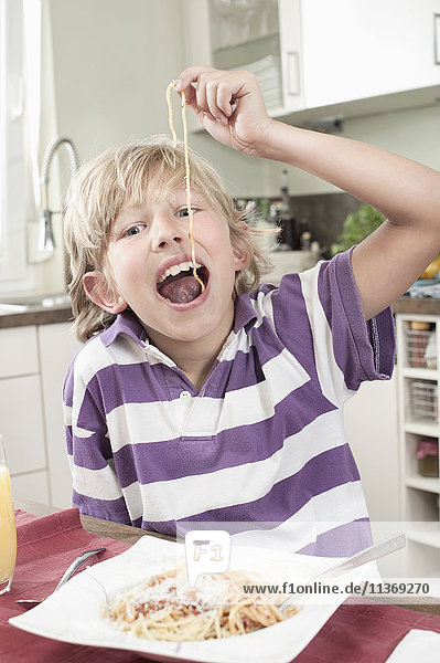 Portrait of a boy eating spaghetti in funny way