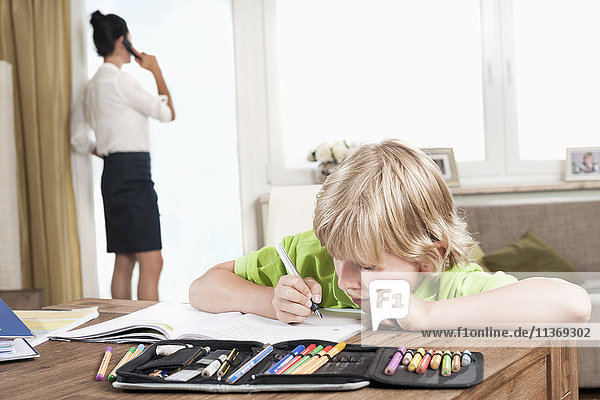Boy studying while mother has business call