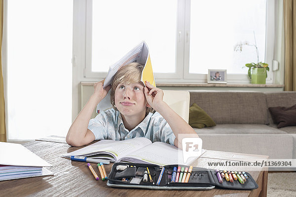 Gelangweilter Junge mit offenem Buch auf dem Kopf