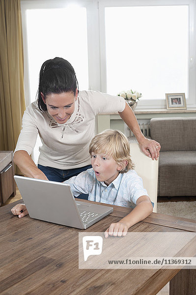 Woman with her son using laptop in living room