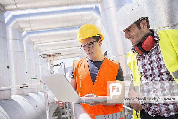 Ingenieur und Arbeiter in einer Besprechung mit Laptop im geothermischen Kraftwerk