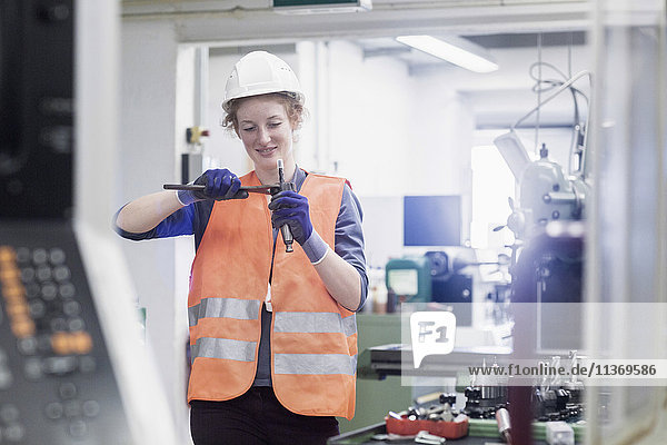 Junge Ingenieurin bei der Reparatur eines Maschinenteils in einer Industrieanlage