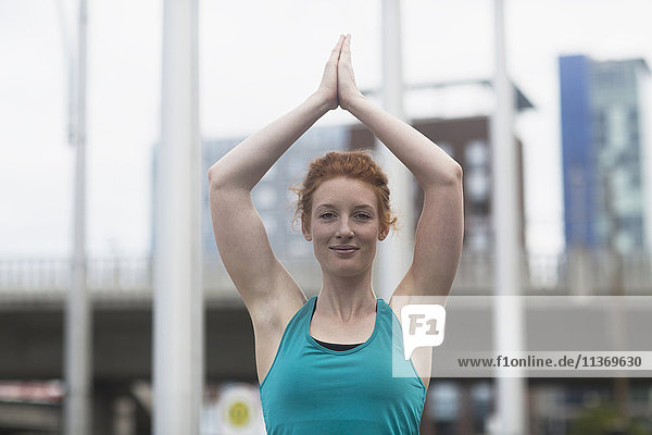 Porträt einer jungen Frau  die in der Lotus-Pose Yoga in einer städtischen Stadt macht