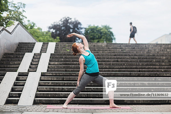 Junge Frau macht Yoga auf einer Treppe in einer Großstadt