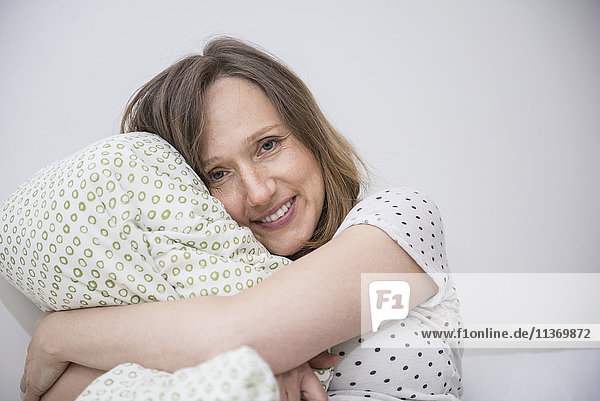 Happy pregnant woman cuddling her pillow in bed