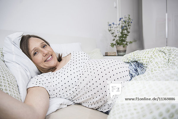 Happy pregnant woman lying in bed