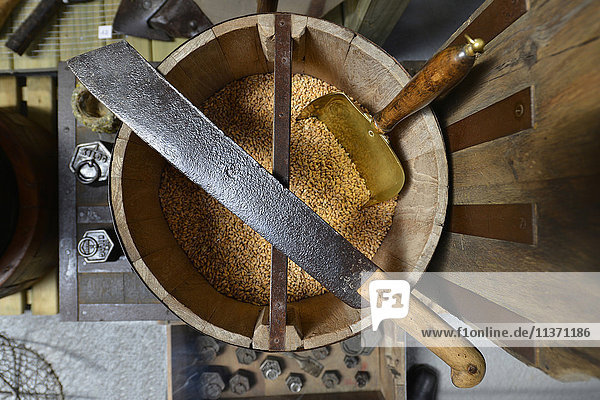 Frankreich  alte Machete auf einem Holzeimer mit Weizenkörnern. Kupferschaufel in Körnern