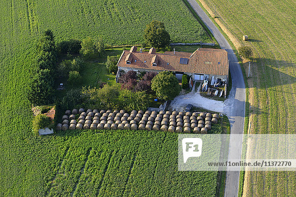 Frankreich  Dordogne  Luftaufnahme eines Hauses inmitten eines Feldes  umgeben von Heuhaufen