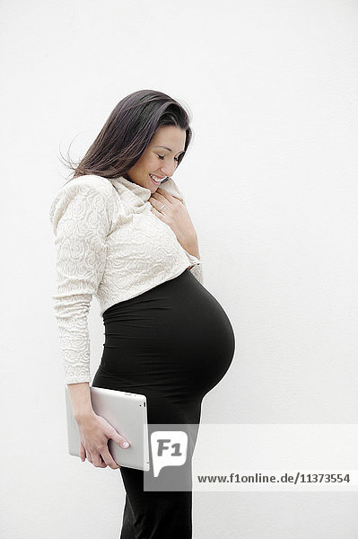 Pregnant young woman holding digital tablet