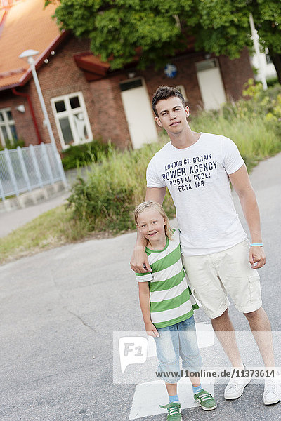 Young man with little brother standing in street