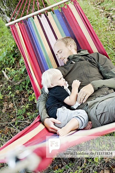 Mann ruht sich mit Sohn in Hängematte aus