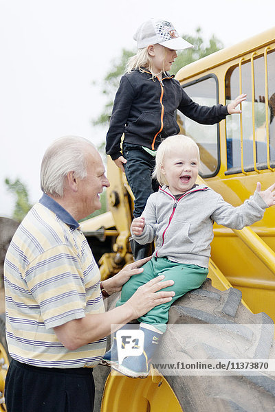 Grandfather with grandchildren by tractor