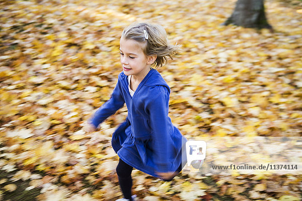 Mädchen läuft zwischen Herbstblättern