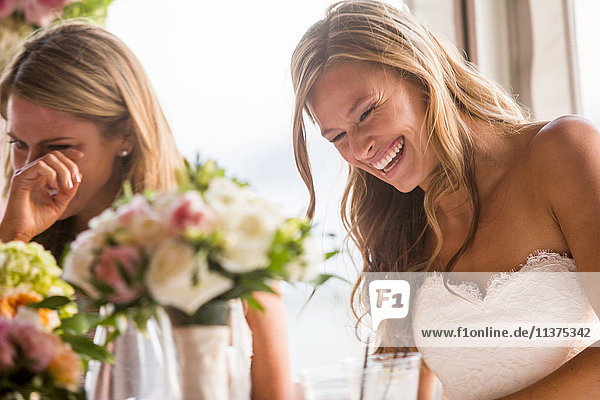 Caucasian brides laughing at table