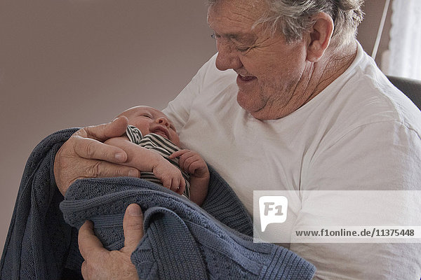 Caucasian grandfather holding baby grandson