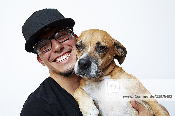 Lächelnder hispanischer Mann umarmt Hund