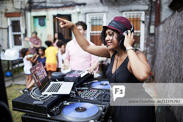 Mixed Race DJ spielt Musik auf einer Party im Hinterhof