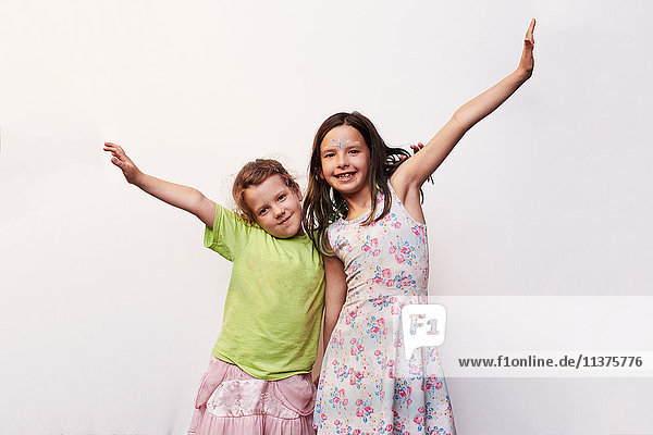 Portrait of smiling Caucasian girls with arms raised