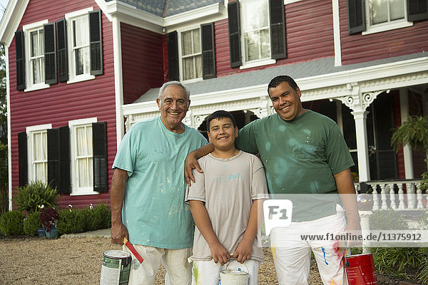 Smiling Hispanic men and boy posing with paint cans