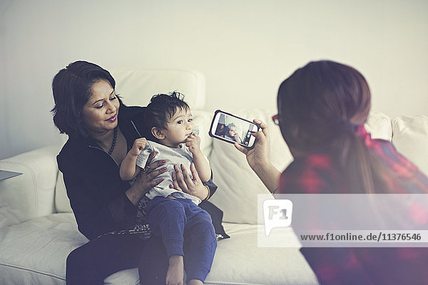 Indische Frau fotografiert Mutter und Sohn mit dem Handy